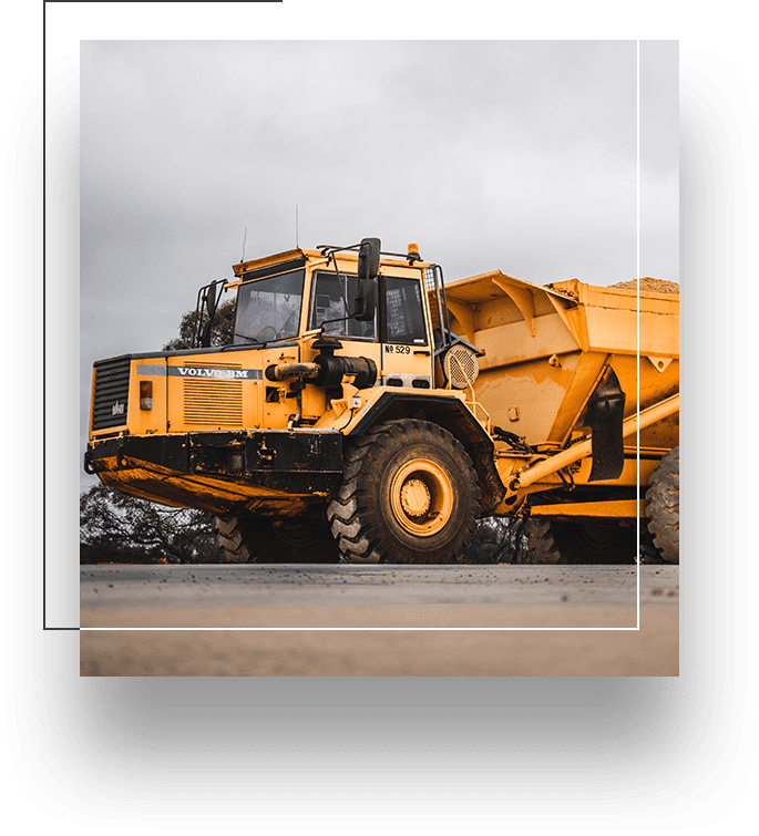 A yellow dump truck is parked on the side of the road.