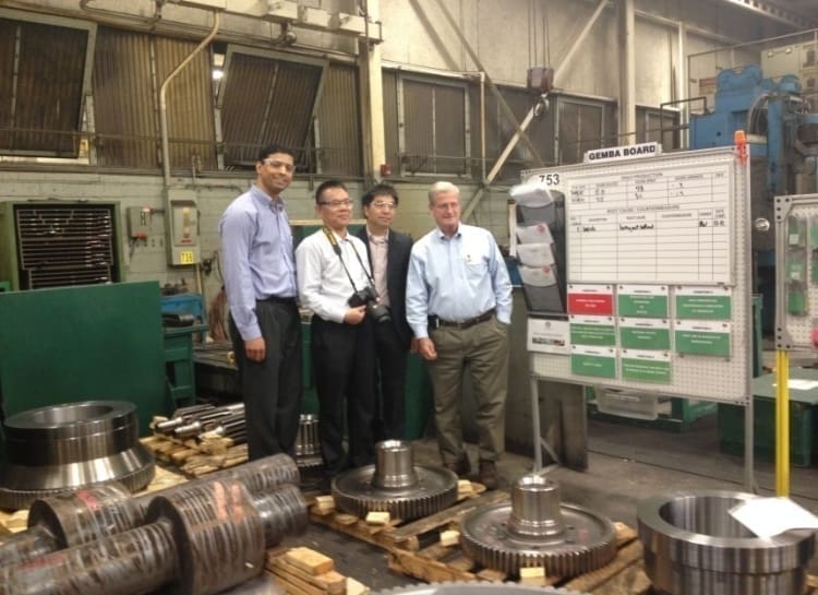 Four men standing in a room with machinery.