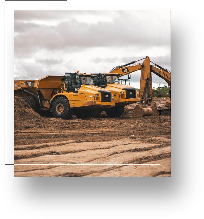 A yellow dump truck is parked in the dirt.