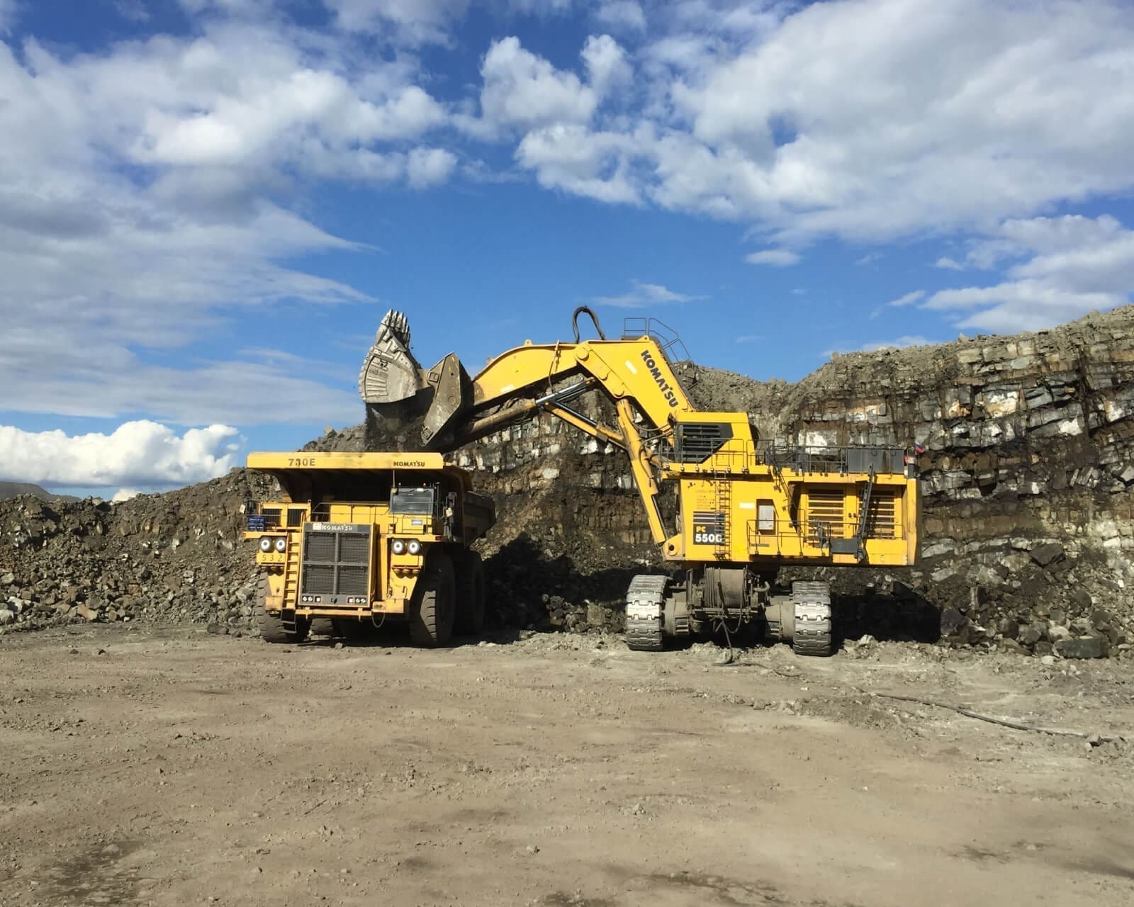 A large yellow truck is parked next to a dump truck.