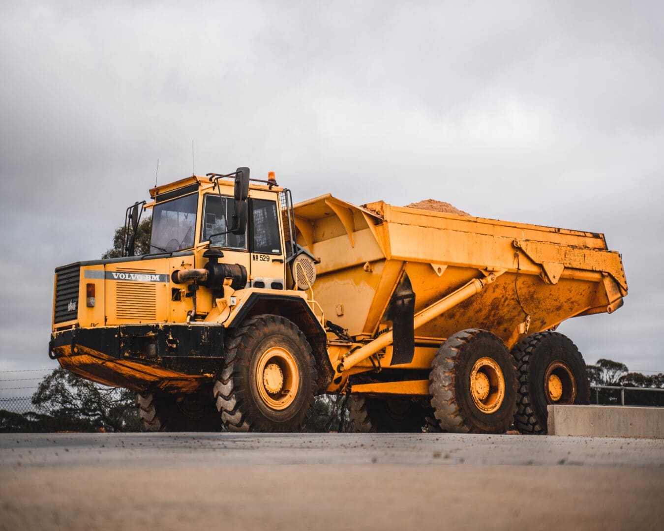 A yellow dump truck is parked on the side of the road.